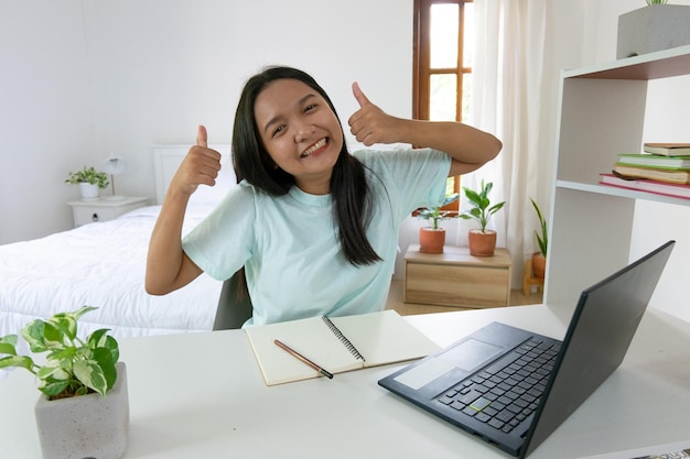 自宅での寝室学習でラップトップで勉強している若い女の子