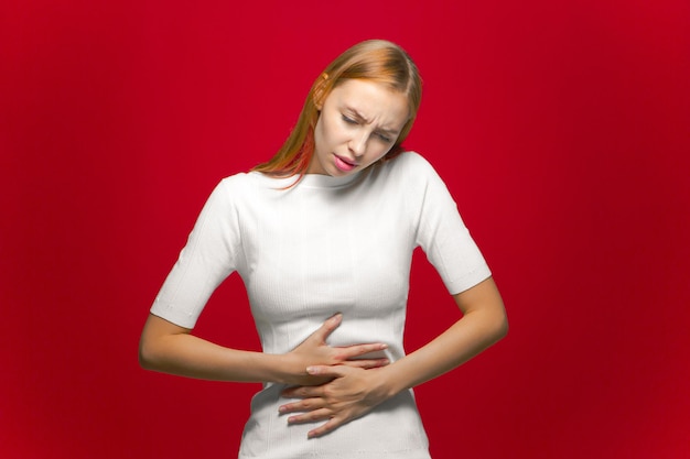 Young girl suffer stomachache abdominal pain diarrhoea or menstrual ache on red background woman