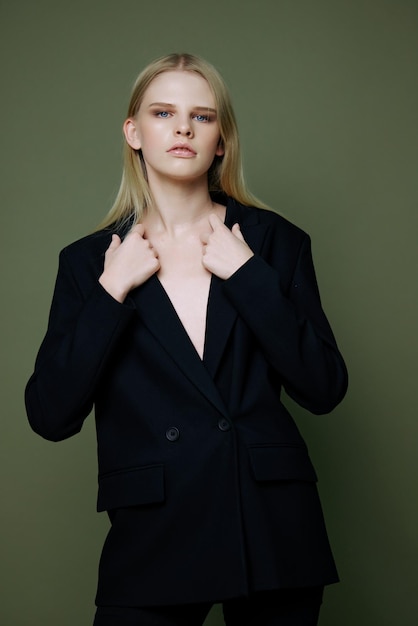 A young girl in a suit posing in the studio on a green olive background is an excellent offer banner for a clothing brand New concept collection