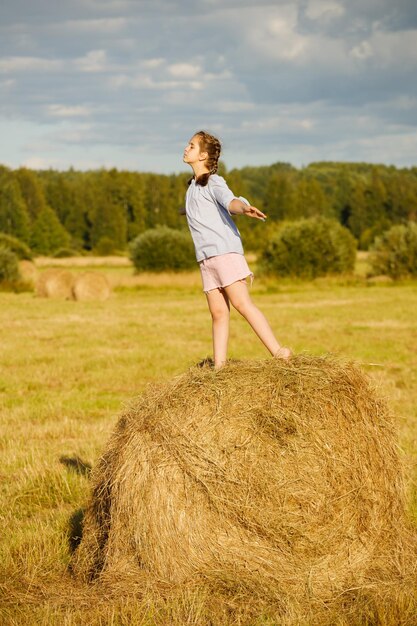 Foto ragazza in un campo estivo. su un rotolo di fieno.