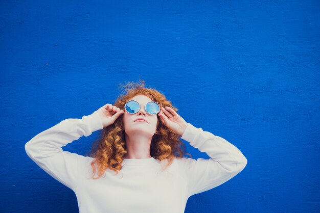 молодая девушка в солнечных очках на синем фоне