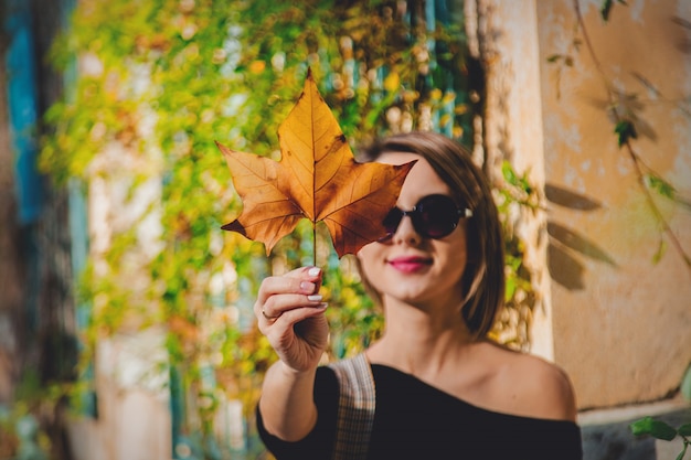 Photo young girl in sunglasses holding a leaf