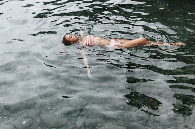 Young girl swims in the sea in the rain