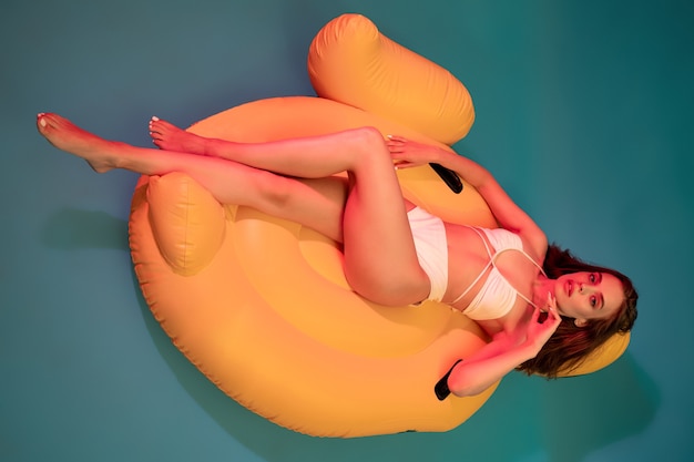 Young girl in swimsuit lying on yellow inflatable mattress