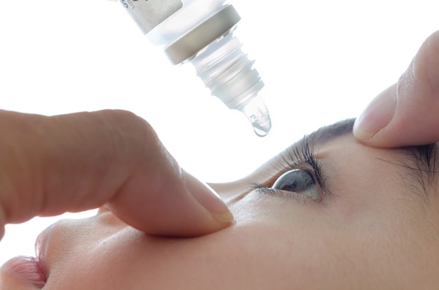 Young girl takes care of her eyes with eye drops.