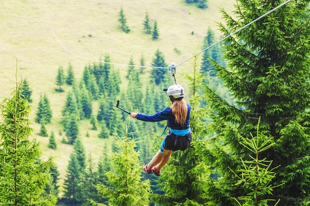 A young girl takes a picture of herself on a cellphone while descending on a zipline