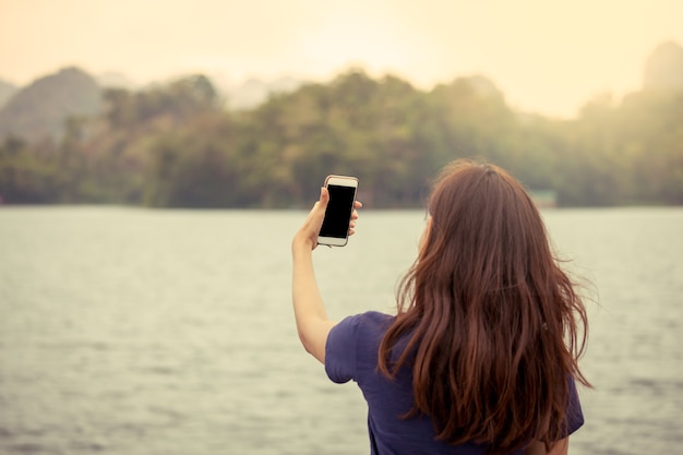 Young girl taking selfie on mobile phone while enjoying her vacation holidays in vintage color tone