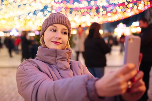 クリスマスの夜に屋外で自撮りをする若い女の子