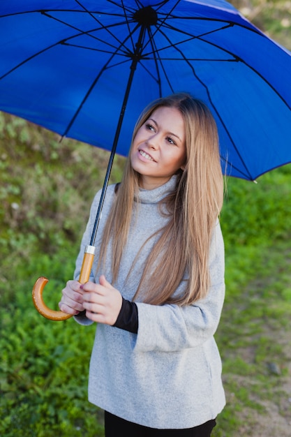 Young girl taking a walk with a blue umbrella