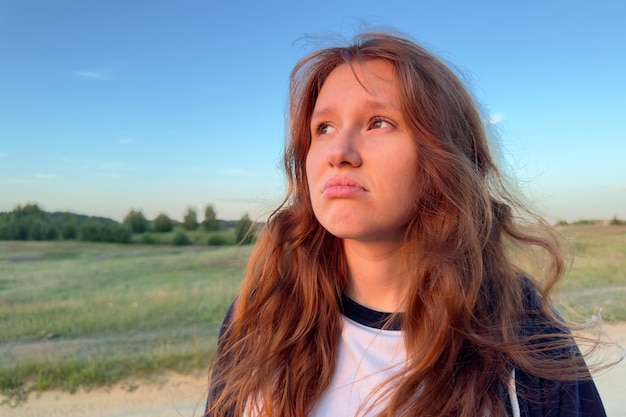 Young girl teenager in the field in nature upset sad frightened