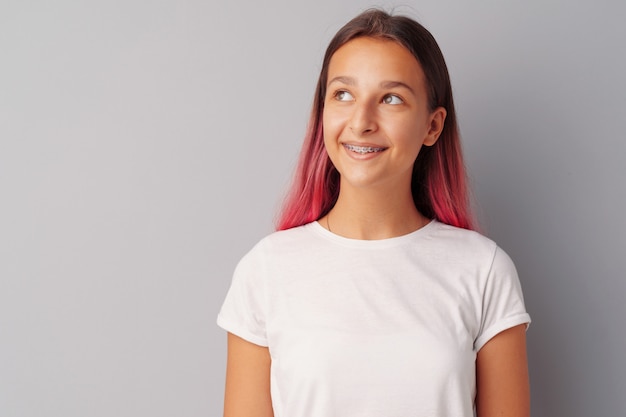 Young girl teenager with pink hair happy and smiling over gray background