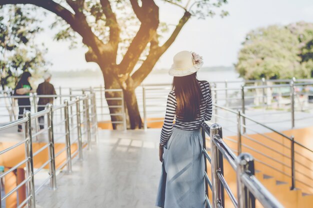 Turista della ragazza da dietro con il cappello. in piedi sulla passerella del balcone di ferro.