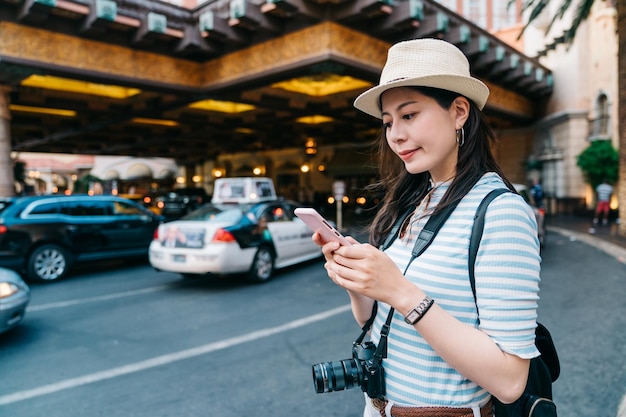 高級ホテルのロビーで彼女を迎えに行くのを待っている間、携帯電話で彼女の友人に連絡する若い女の子の旅行者。カジノラスベガスから目立つ携帯電話のテキストメッセージを使用して美しい女性の観光客