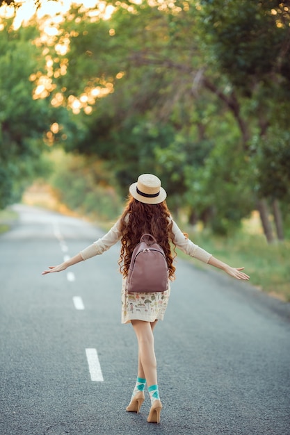 Il viaggiatore della ragazza gode del viaggio. donna felice che cammina sulla strada.