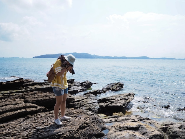 Young girl traveler taking photographs of summer beach. 