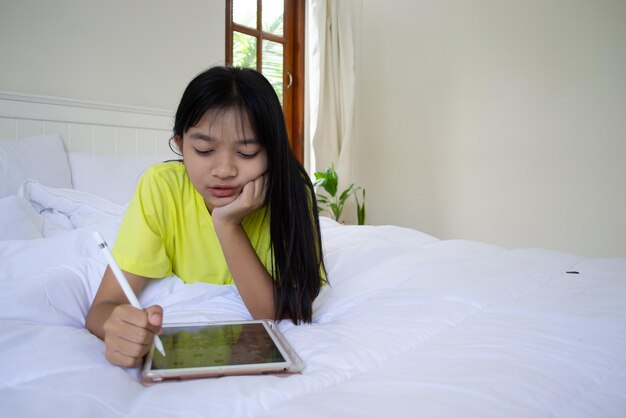 若い女の子は自宅の寝室のベッドでラップトップを使用します