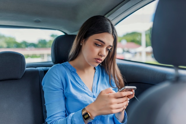 Young girl uses a mobile phone in the car 