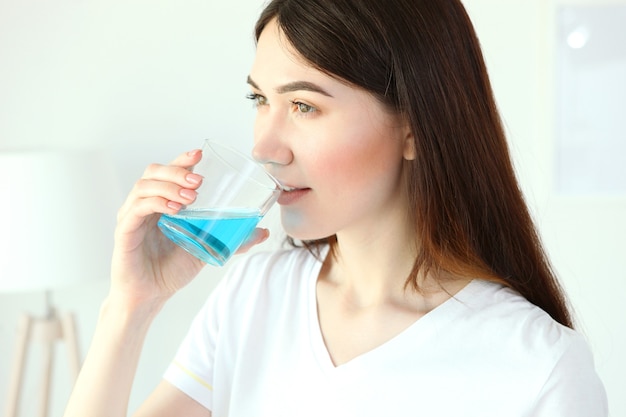 Молодая девушка использует жидкость для полоскания рта дома крупным планом