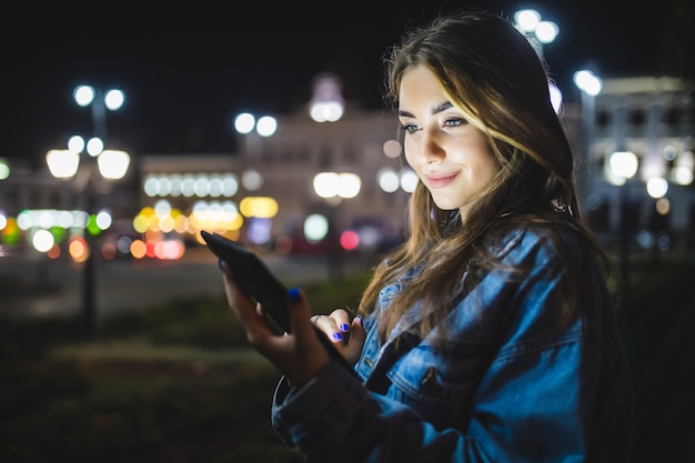 Ragazza giovane utilizzando la tavoletta digitale di notte