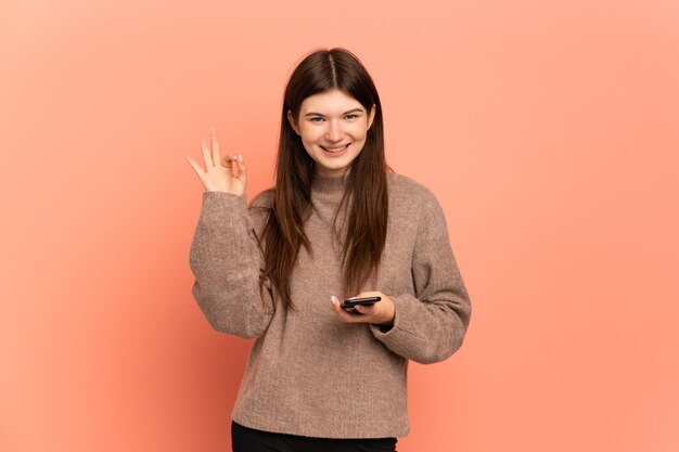 Young girl using mobile phone and doing OK sign