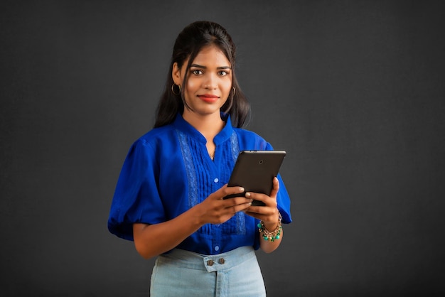 灰色の背景に携帯電話やスマートフォンを使用して若い女の子