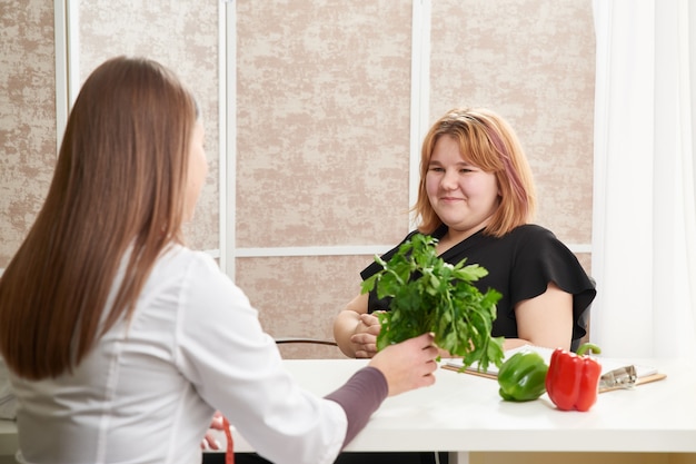 ダイエットプログラムの助けを借りて体重を減らすために栄養士を訪問している若い女の子