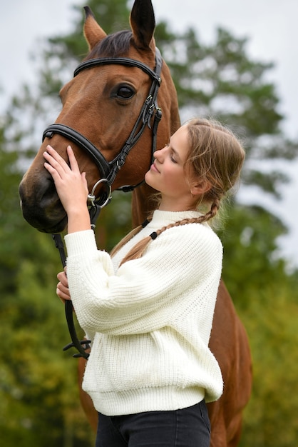 Young girl walking with a horse in nature.