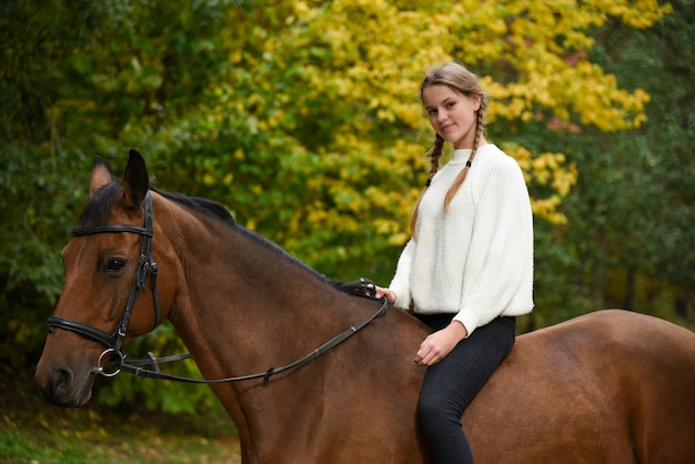 Молодая девушка гуляет с лошадью на природе.