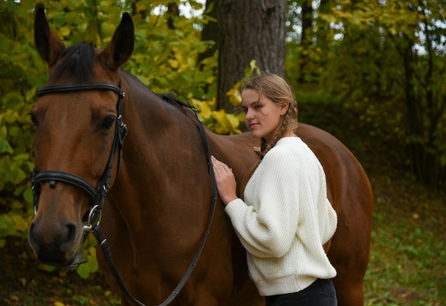 Young girl walking with a horse in nature.