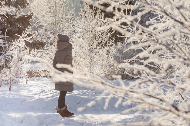 若い女の子が雪に覆われた都市公園を歩く