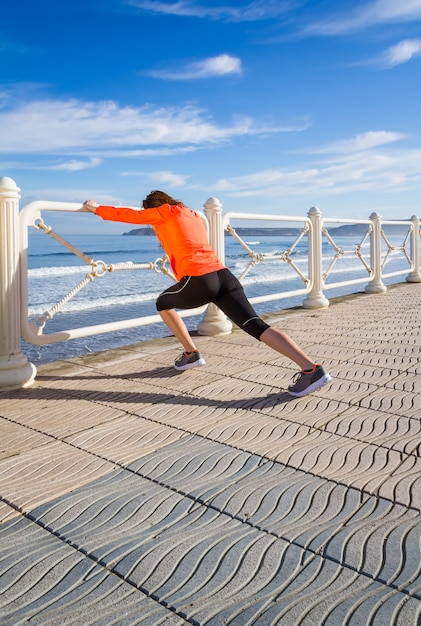 Young girl warming before running in a promenade