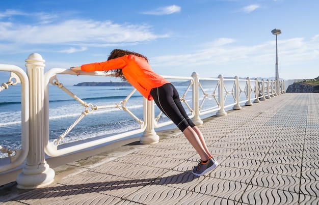 Young girl warming before running in a promenade