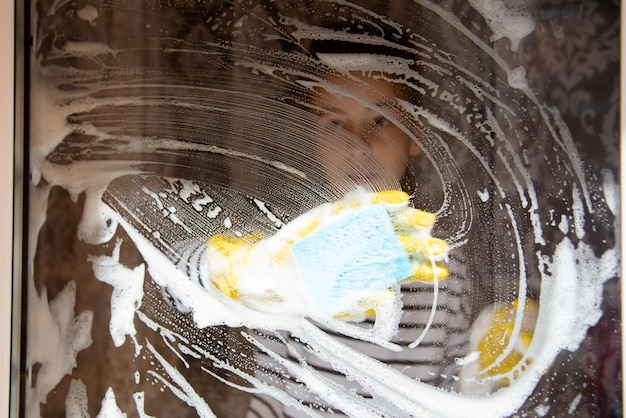 A young girl washes the windows of her house. Homework. Lifestile.