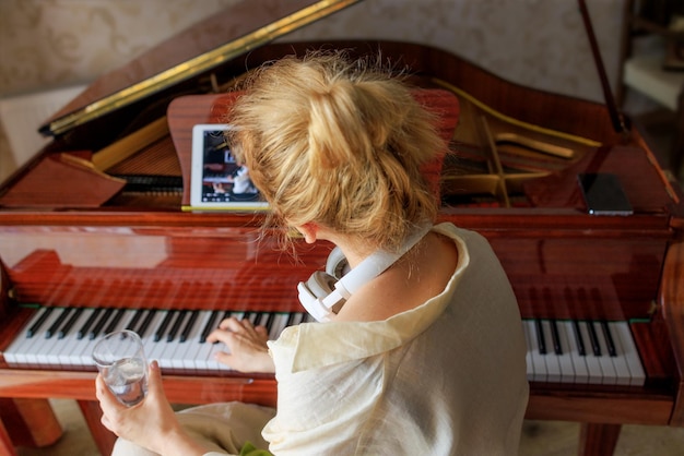 Девушка смотрит обучающее видео по игре на фортепиано, хочет выучить песню