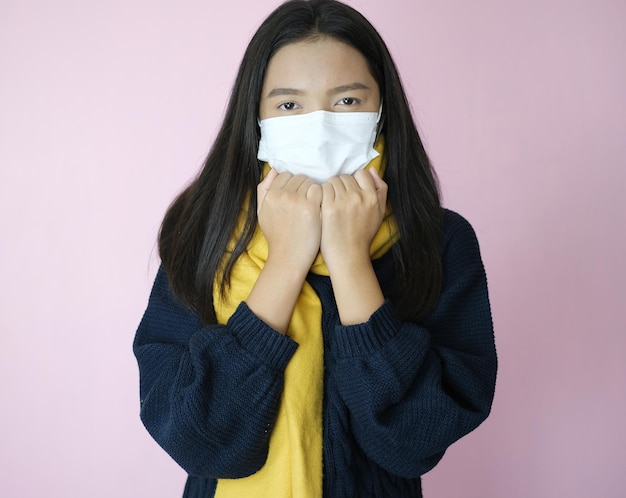 Young girl wear mask and sweater on pinkbackground.