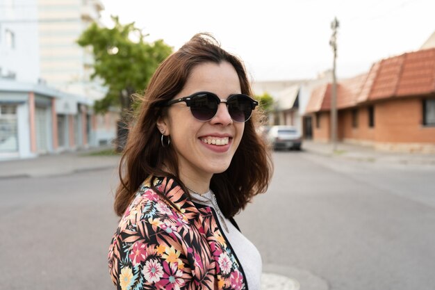 Young girl wearing dark sunglasses and smiling as she crosses the street