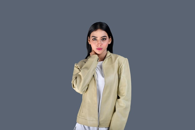 Young girl wearing jacket front pose hand on neck on grey background indian pakistani model