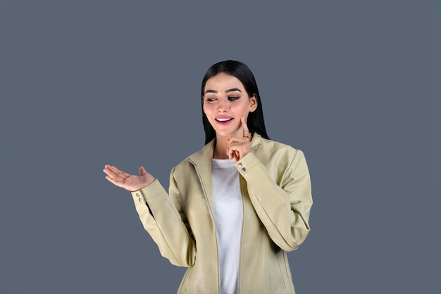 灰色の背景に笑顔で正面を向いているジャケットを着ている若い女の子インドのパキスタンモデル