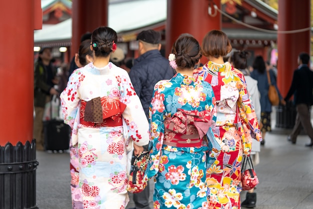 Маленькая девочка нося японское кимоно стоя перед виском Sensoji в токио, Японии.