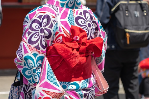 東京の浅草寺の前に立っている日本の着物を着た少女。