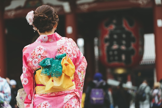 Young girl wearing Japanese kimono standing in front of Sensoji Temple in Tokyo, 