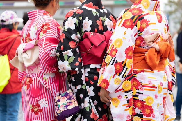 東京の浅草寺の前に日本の着物姿で立っている若い女の子