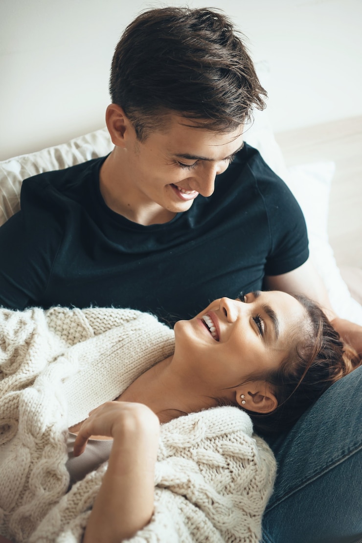 Photo young girl wearing a knitted sweater smiling at her lover lying on his knees