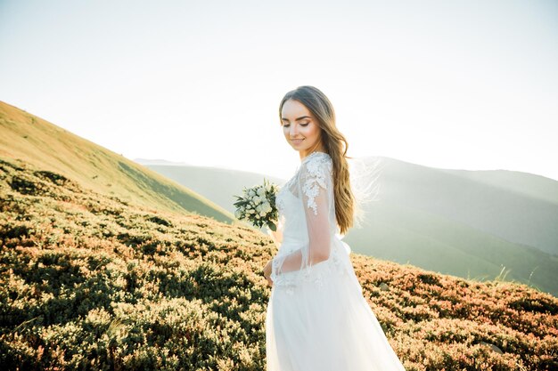 young girl in a wedding dress walk in the mountains at sunrise in the morning