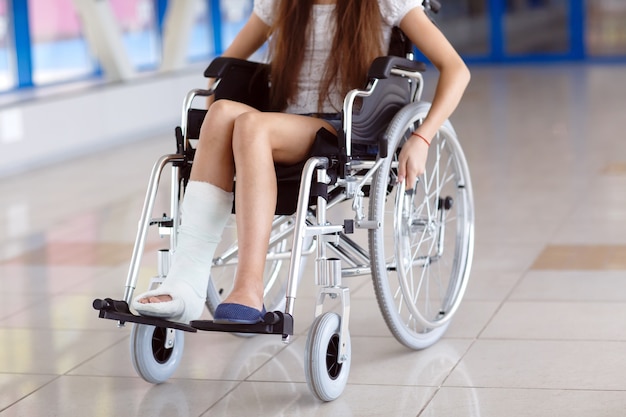 Una ragazza su una sedia a rotelle è in piedi nel corridoio dell'ospedale.