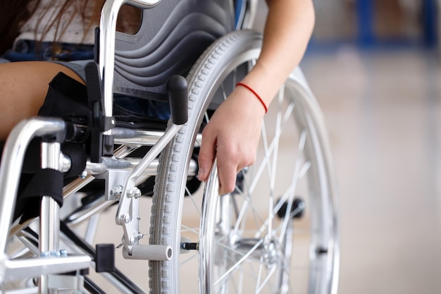 Молодая девушка в инвалидной коляске стоит в коридоре больницы.