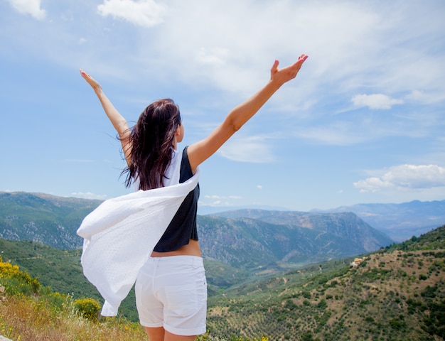 Young girl in white clothes standing on rock in Greece