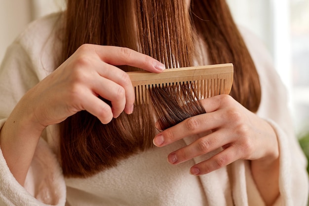 a young girl in a white coat takes care of her hair at home