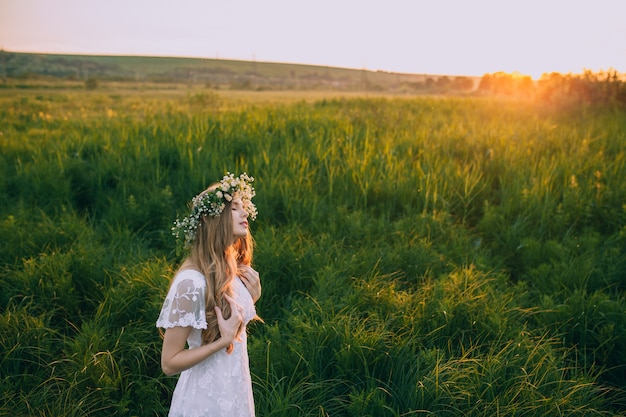 Young girl in a white dress in the meadow. Woman in a beautiful long dress posing on a meadow