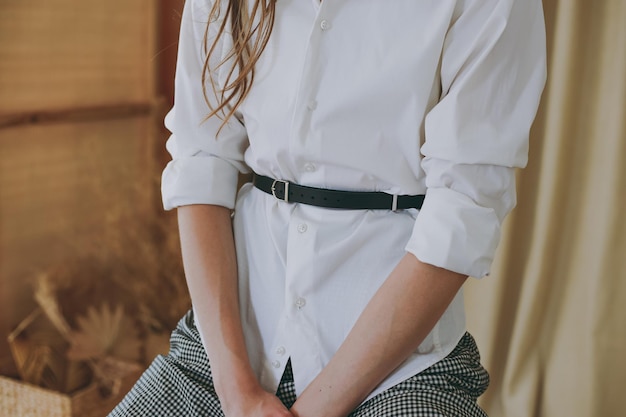 Young girl in a white office shirt trying on a leather belt